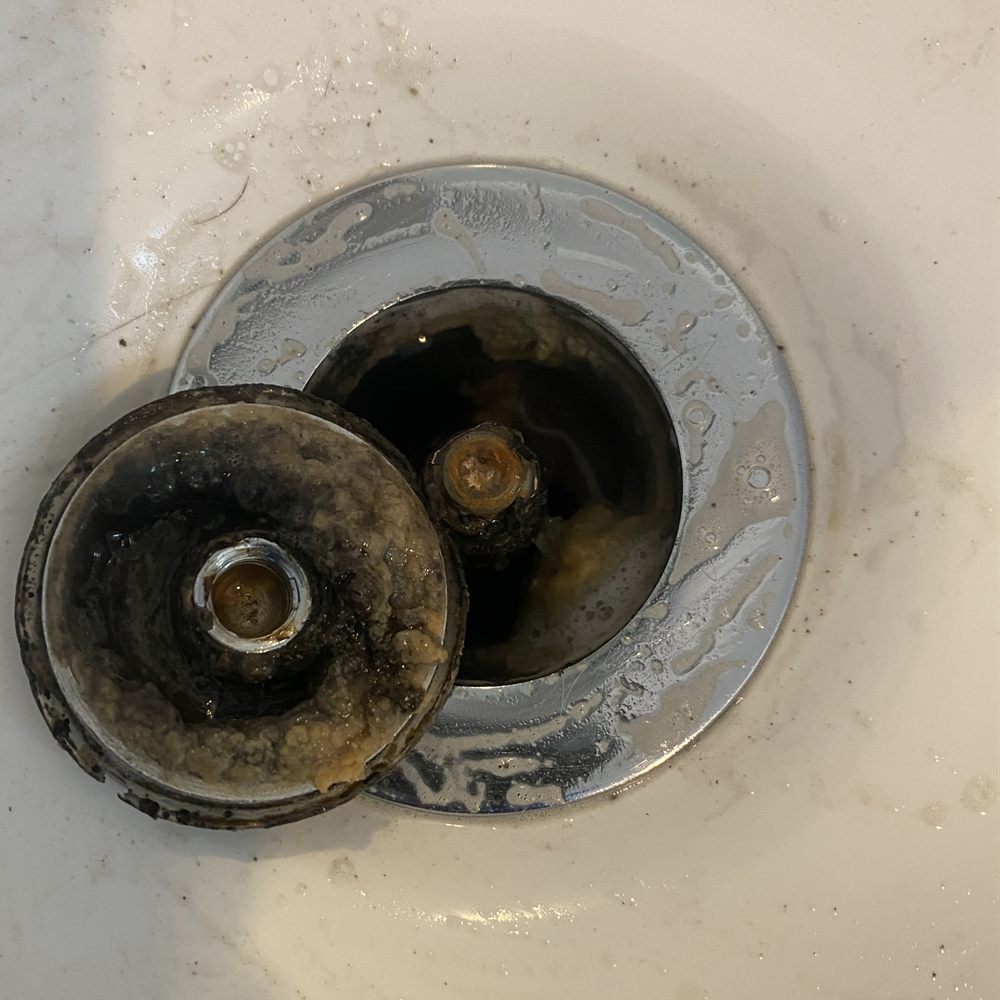 Before cleaning: bathroom sink drain and waste plug caked with black grime and soap scum