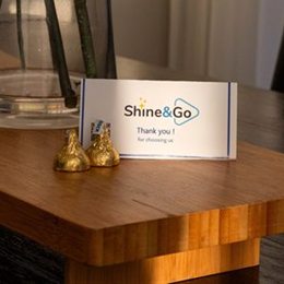 Two gold-wrapped chocolates beside a Shine&Go NZ thank-you card, the founders' signature touch left after every clean