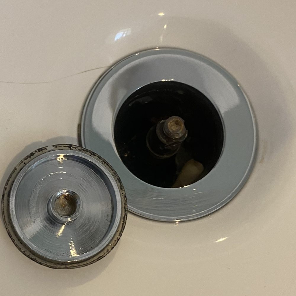 After cleaning: the same bathroom sink drain and waste plug, scrubbed back to bare metal
